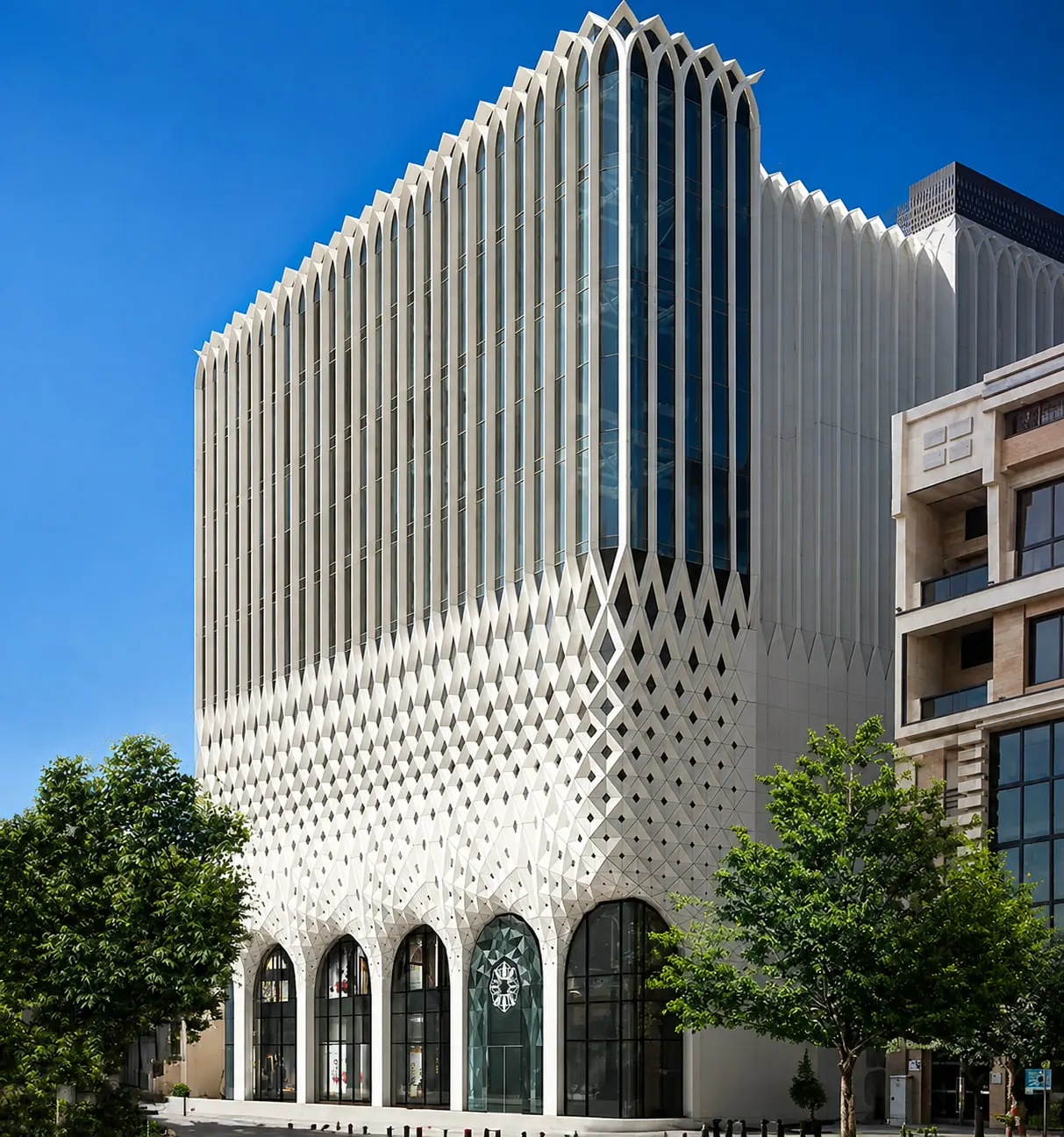 Ansar Cultural Center at the corner, the pointed-arch screen turning with the building
