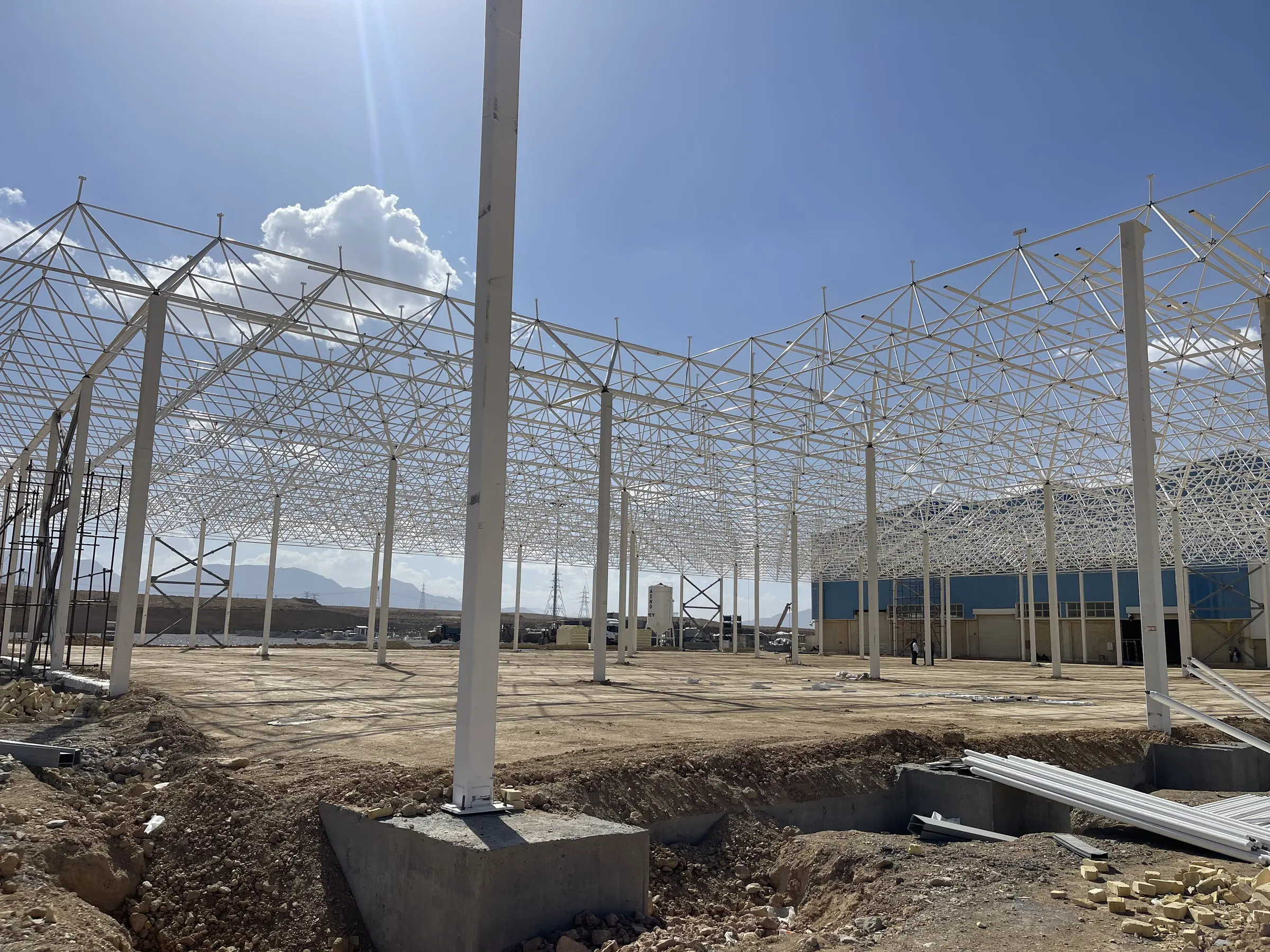 The space-frame roof standing over the factory foundations before the floor slab