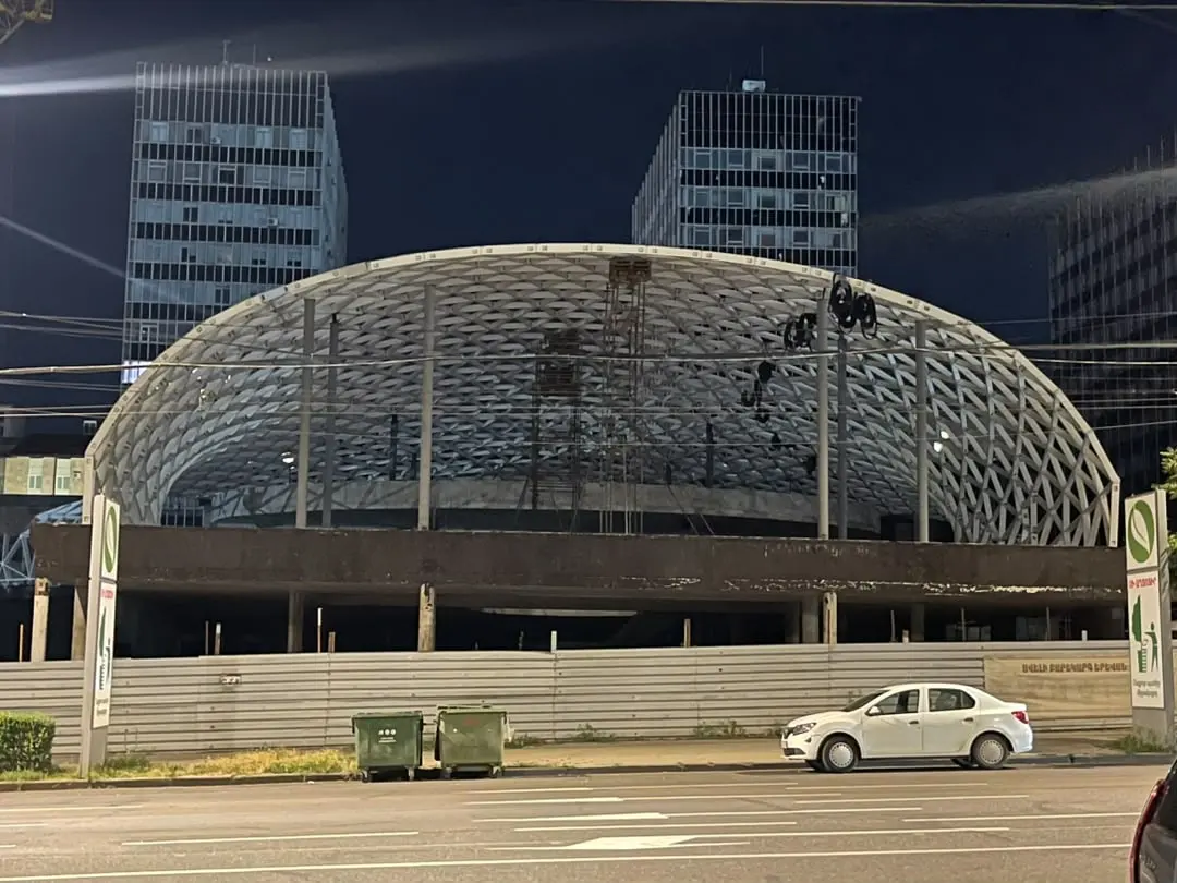 The DOMAINE gridshell from the street at night, the steel erected over the podium