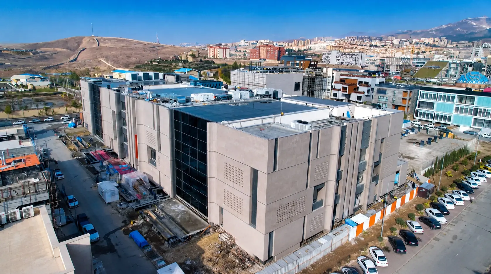 The Fanap campus from the air, the completed precast-clad block in front of the wider district and the hills beyond