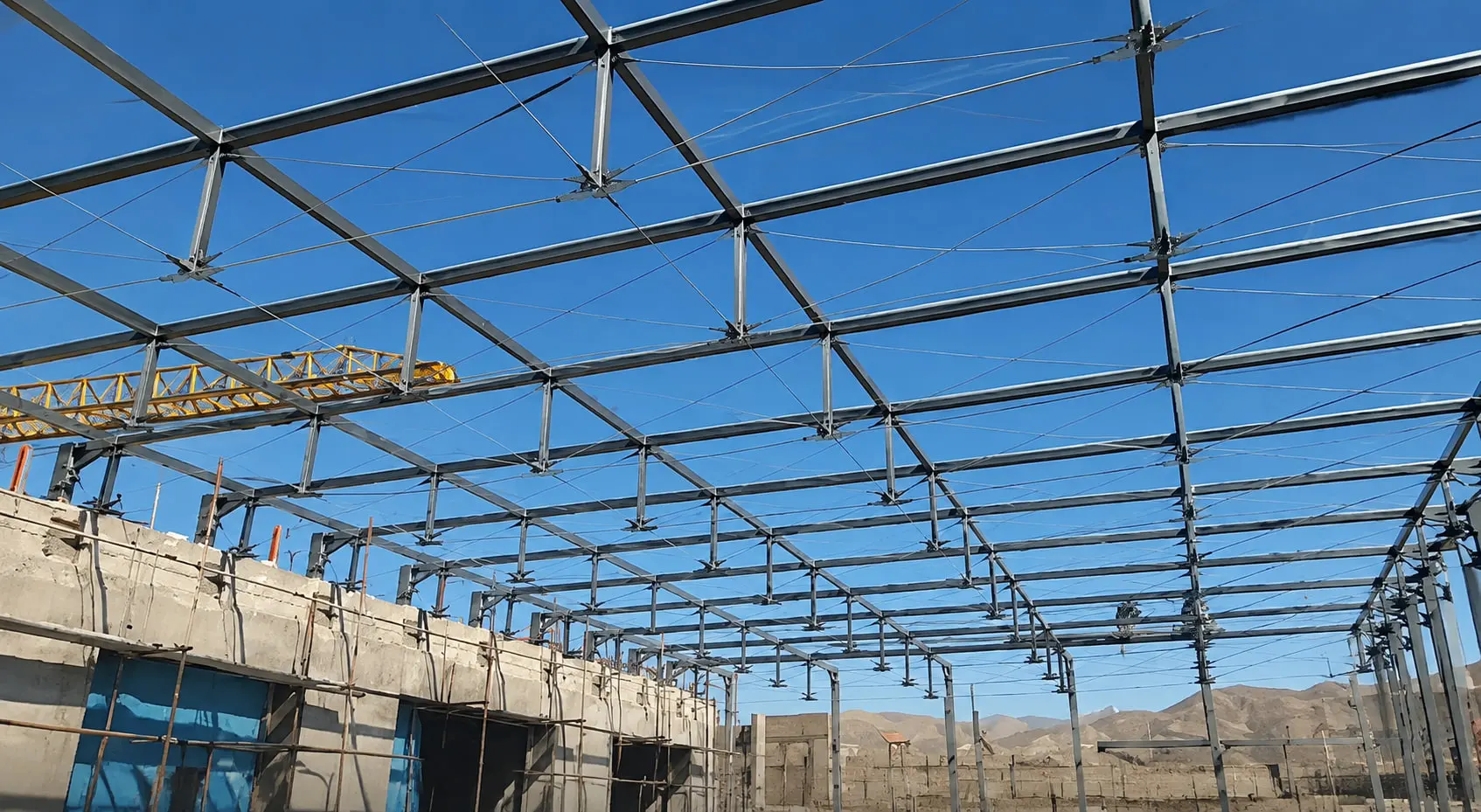 The Fanap roof steel complete before glazing, the tie rods of the cable truss picked out against clear sky