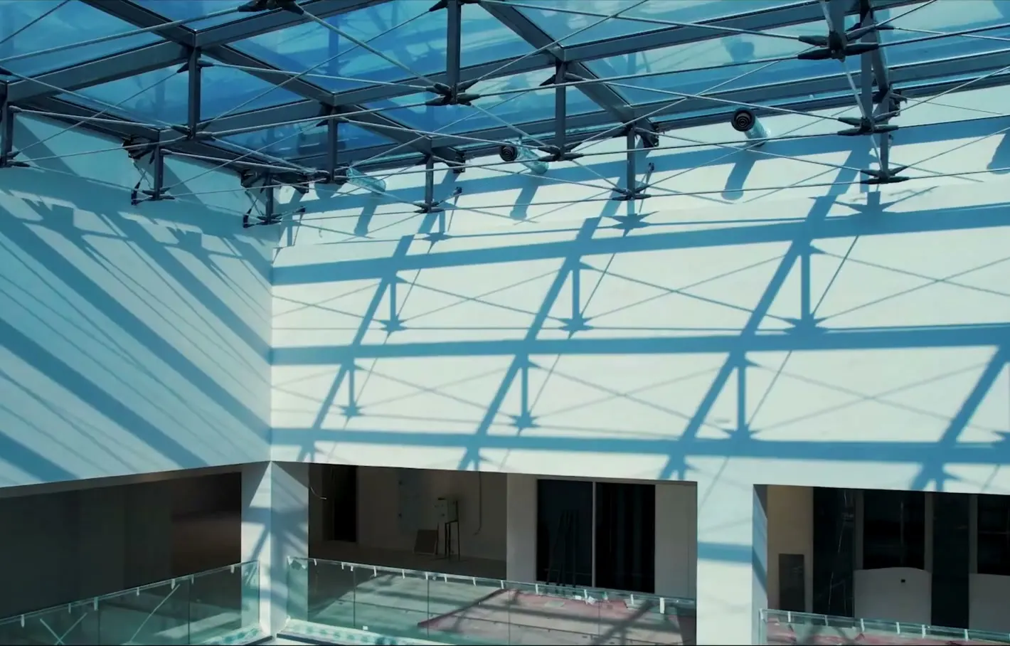 The shadow of the Fanap cable truss roof on a courtyard wall — the steel grid, the struts and the tie rods drawn in sunlight