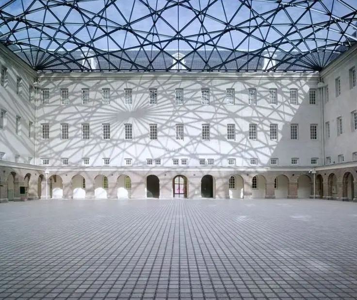 Reference example: a gridded glass atrium roof over a courtyard enclosed by an older building