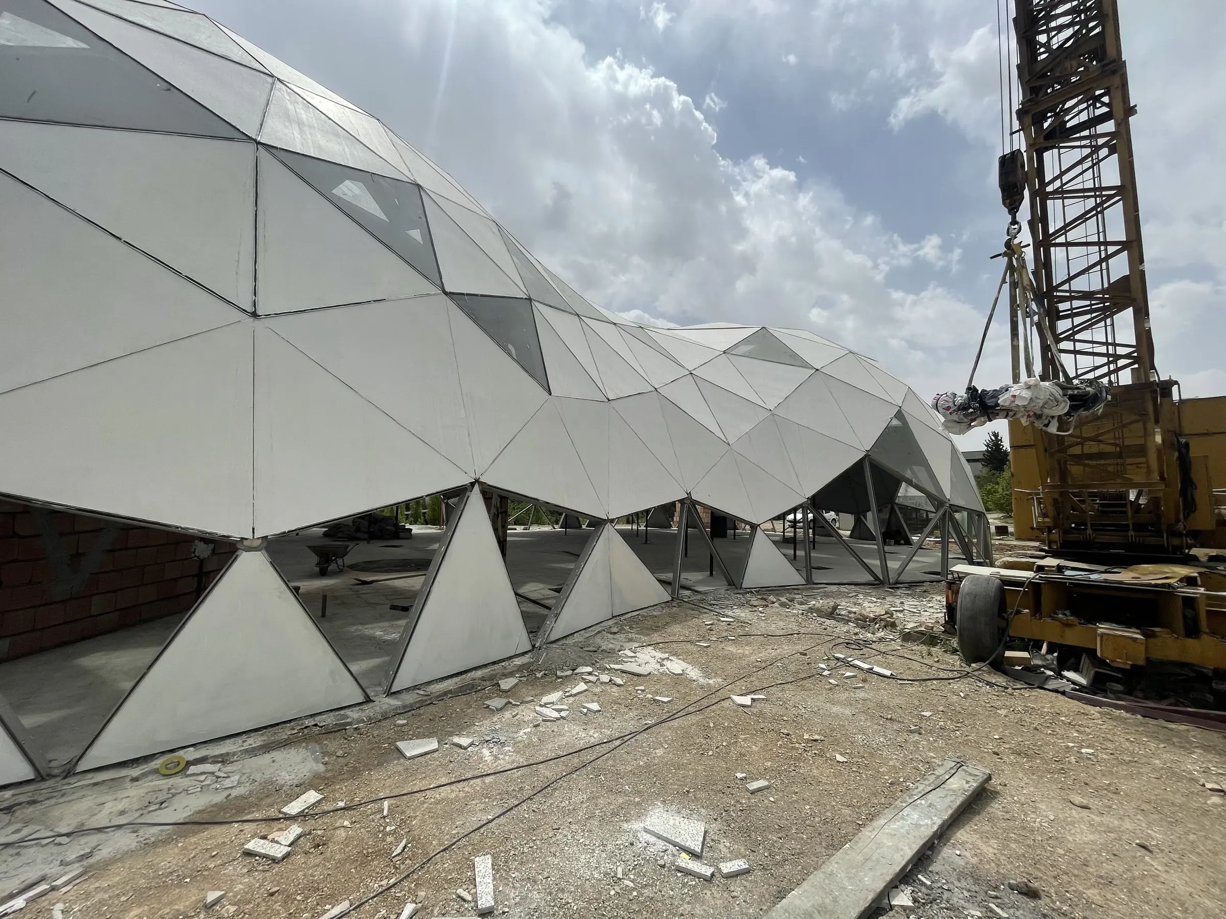 Cladding panels being fixed to the research centre dome, the crane still standing