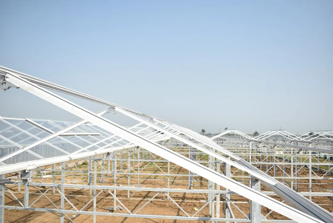 Close view of a greenhouse ridge showing the Venlo arm, push-up bar and ventilation hinge against the sky