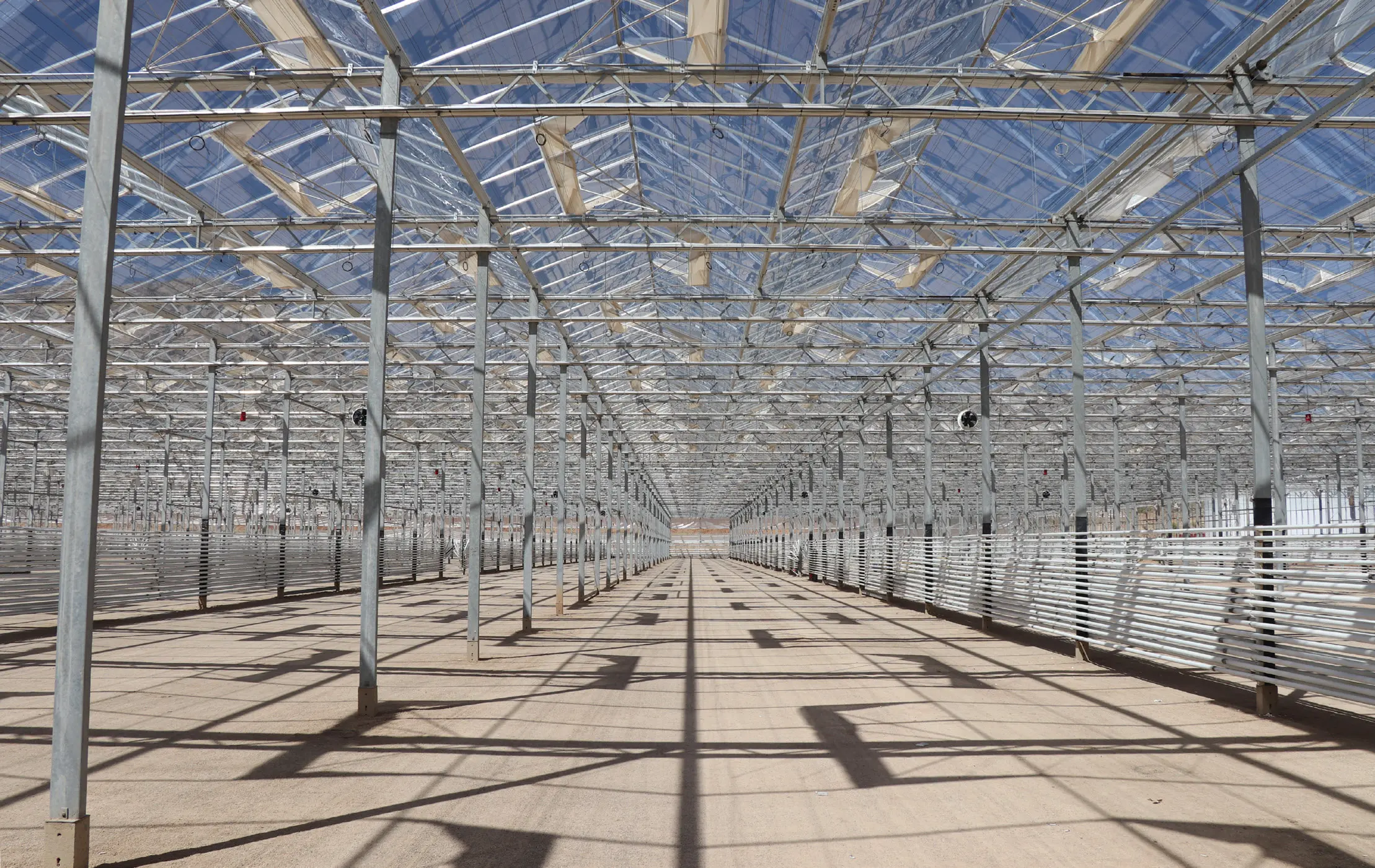 Interior of a completed Venlo greenhouse before planting, looking down the length of the concrete floor between column rows