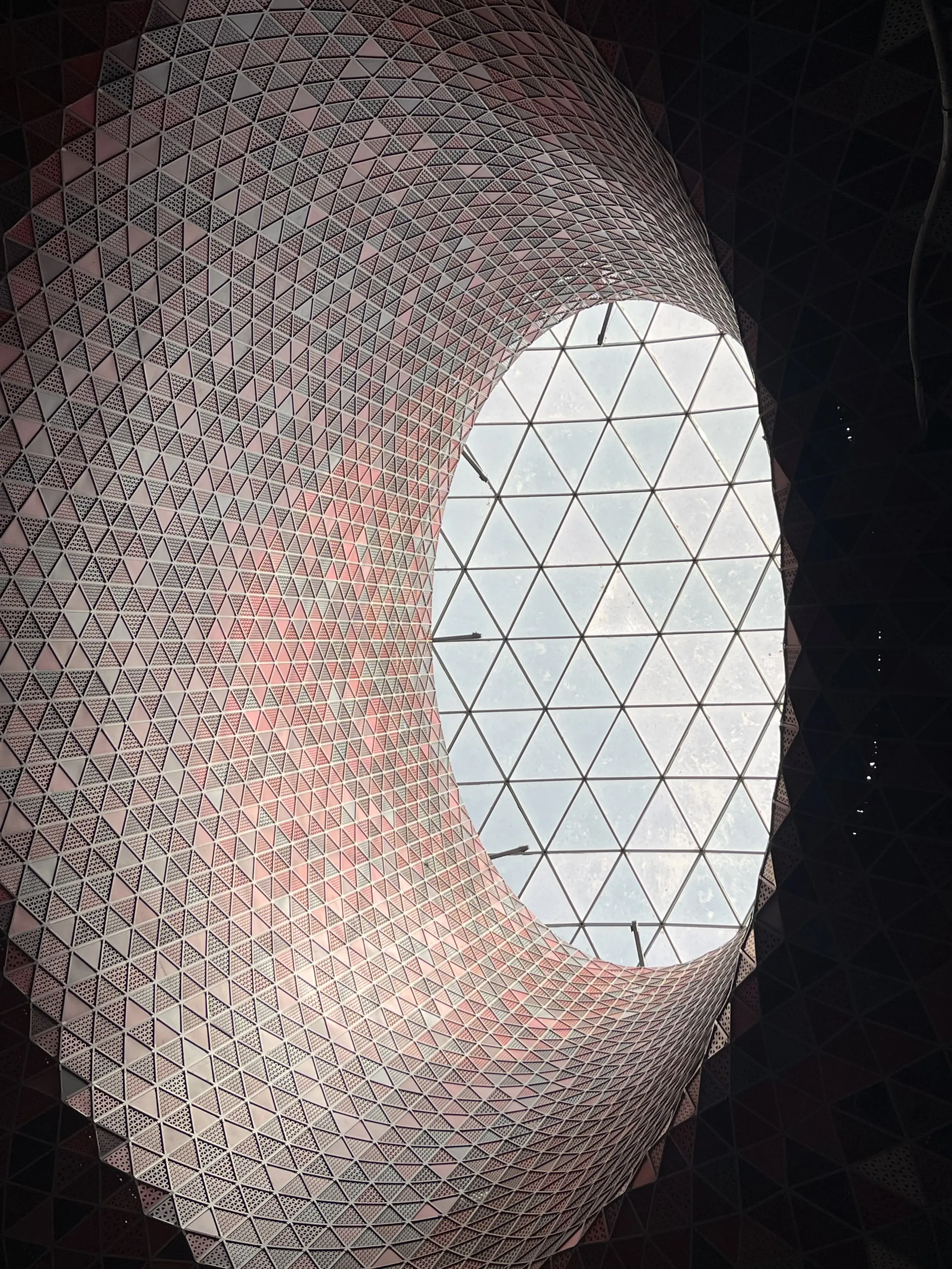 The oculus skylight at Yas Shopping Mall from inside, its triangulated skin drawing daylight down the funnel